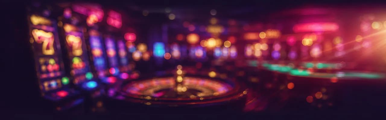 Defocused casino floor with glowing slot machines, a spinning roulette wheel and live-dealer table lights